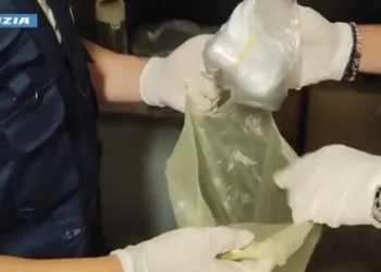 Agenti con guanti bianchi estraggono da una busta un involucro di sostanza bianca, sequestro di cocaina a Gela