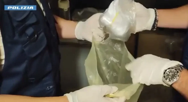 Agenti con guanti bianchi estraggono da una busta un involucro di sostanza bianca, sequestro di cocaina a Gela