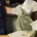 Agenti con guanti bianchi estraggono da una busta un involucro di sostanza bianca, sequestro di cocaina a Gela