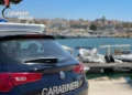 Auto dei Carabinieri di Ragusa ferma su una banchina, con un porticciolo e barche ormeggiate sullo sfondo