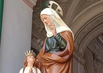 Statua di Sant'Anna accanto a Maria Bambina con corona dorata e mani giunte, sotto un arco decorato