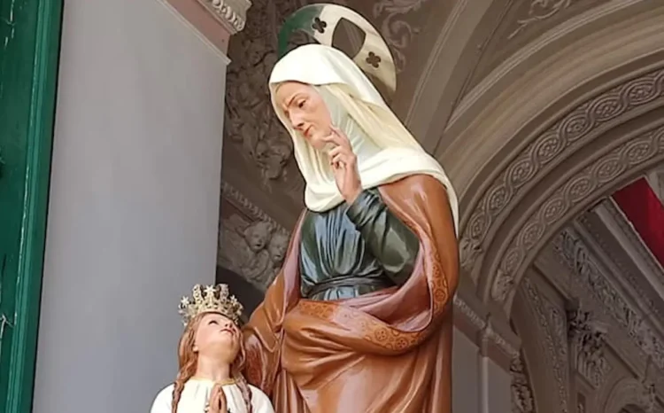 Statua di Sant'Anna accanto a Maria Bambina con corona dorata e mani giunte, sotto un arco decorato