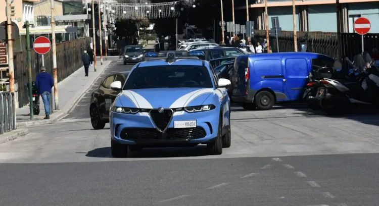 Auto della Polizia di Stato in transito su una via cittadina tra traffico e pedoni