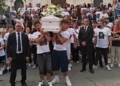 Giovani in maglietta bianca portano il feretro durante i funerali a Pozzallo