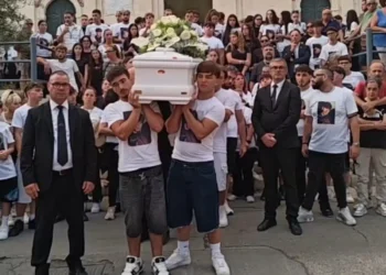 Giovani in maglietta bianca portano il feretro durante i funerali a Pozzallo