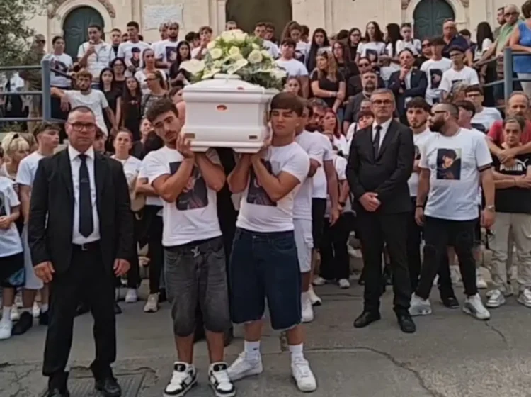 Giovani in maglietta bianca portano il feretro durante i funerali a Pozzallo
