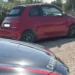 Fiat 500 rossa ferma su uno sterrato, accanto al cofano di un'auto dei Carabinieri