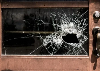 Vetrata di un negozio con il vetro infranto e segni evidenti di effrazione