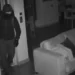 Immagine notturna di sicurezza: un ladro incappucciato entra in casa durante un furto