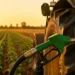 Ugello verde di un distributore di gasolio inserito nel serbatoio di un trattore in un campo al tramonto