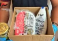 Un carabiniere con guanti blu mostra una scatola con i veleni sequestrati a Ramacca: un barattolo e dei flaconi con la scritta «veleno»