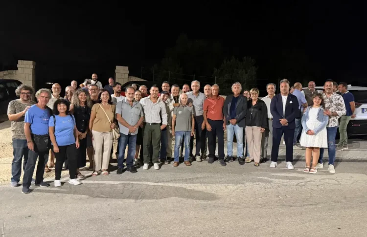 Decine di persone in posa di notte su una strada di campagna per l'accensione dell'illuminazione sulla Spinazza a Donnalucata