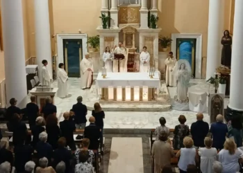 Messa vista dall'alto: celebranti all'altare, fedeli in piedi e, sulla destra, la statua dell'Immacolata