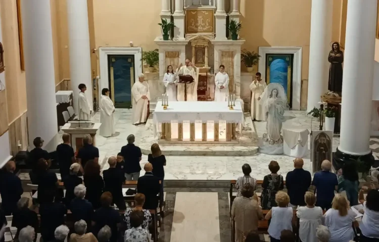 Messa vista dall'alto: celebranti all'altare, fedeli in piedi e, sulla destra, la statua dell'Immacolata