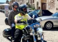 Due persone in sella a una moto con caschi integrali davanti al Castello di Donnafugata, a Ragusa, tra auto d'epoca