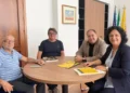 Quattro persone a un tavolo rotondo con opuscoli gialli del progetto In viaggio con i Cabrera, bandiere sullo sfondo