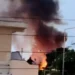 Colonna di fumo nero e fiamme vicino alle case: incendio a Donnalucata, con alcune persone che osservano da un terrazzo