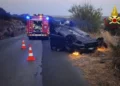 Auto ribaltata su una strada di campagna al crepuscolo, con mezzo dei vigili del fuoco, coni segnaletici e luci blu accese
