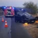 Auto ribaltata su una strada di campagna al crepuscolo, con mezzo dei vigili del fuoco, coni segnaletici e luci blu accese