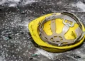 Casco giallo da cantiere appoggiato a terra tra vetri infranti e detriti
