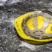 Casco giallo da cantiere appoggiato a terra tra vetri infranti e detriti