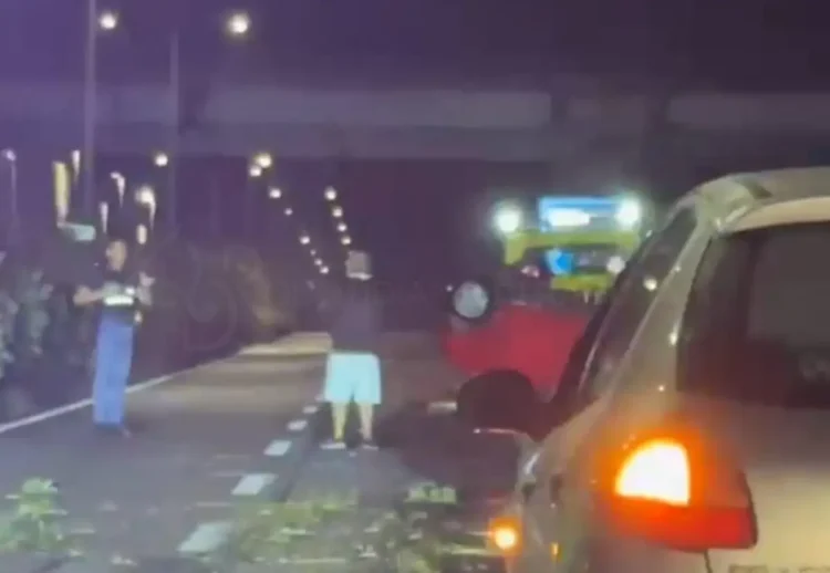 Incidente Ragusa, un’auto rossa ribaltata sulla strada durante la notte, con persone e un’auto in primo piano