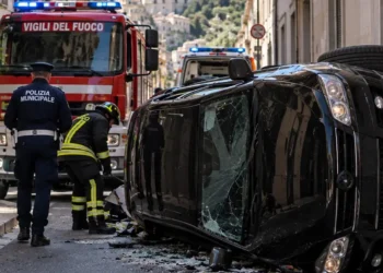 Auto nera ribaltata con vigili del fuoco e soccorritori a Ragusa. Immagine generata con intelligenza artificiale