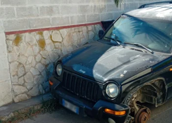 Auto fuoristrada danneggiata con ruota anteriore mancante, ferma vicino a un muro di pietra a Scoglitti