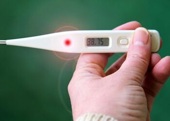 Mano che regge un termometro digitale con 38,75 gradi sul display, febbre alta tipica dei sintomi dell'influenza