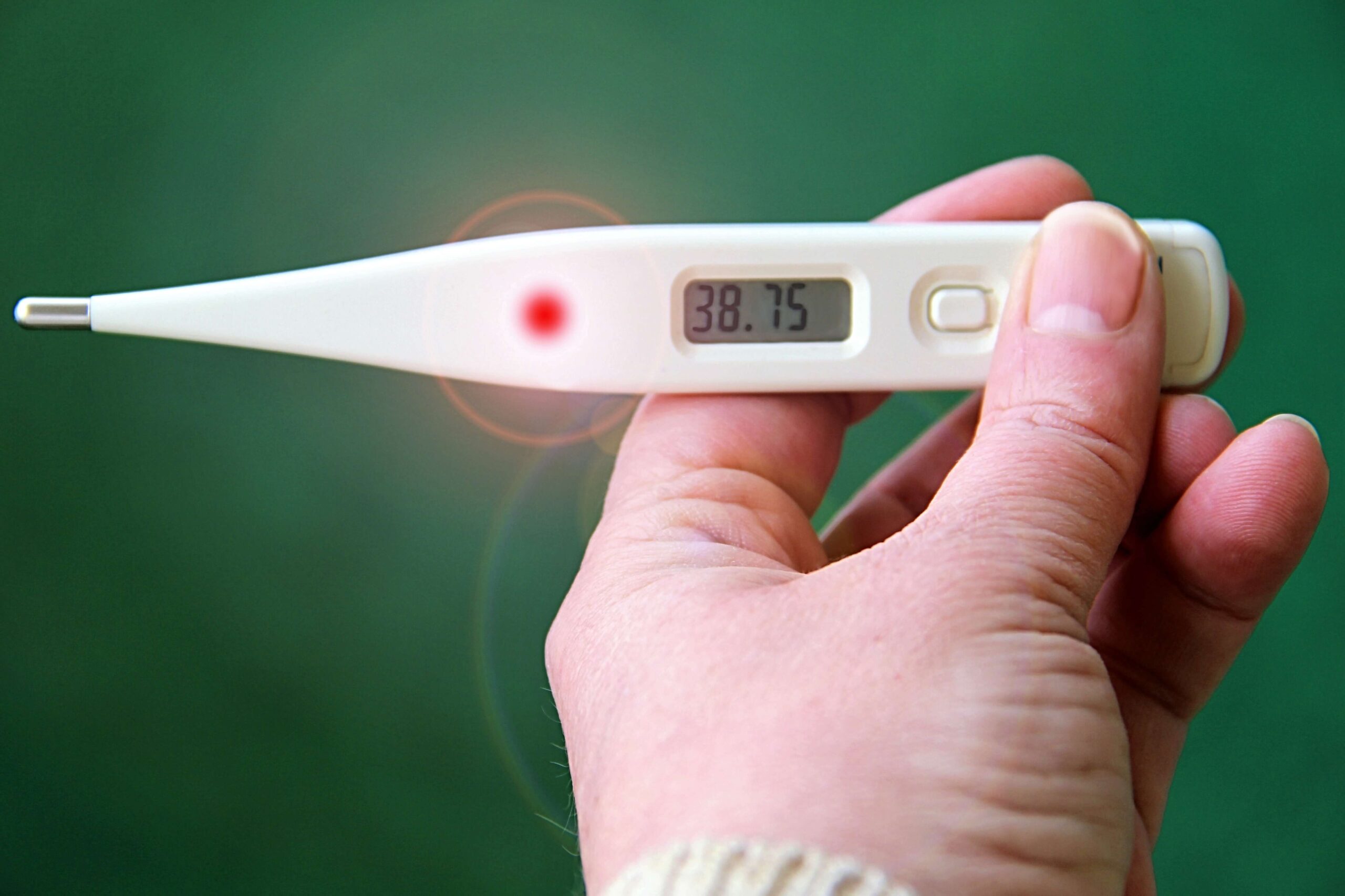 Mano che regge un termometro digitale con 38,75 gradi sul display, febbre alta tipica dei sintomi dell'influenza
