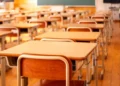 Aula scolastica vuota con banchi e sedie disposti davanti alla lavagna