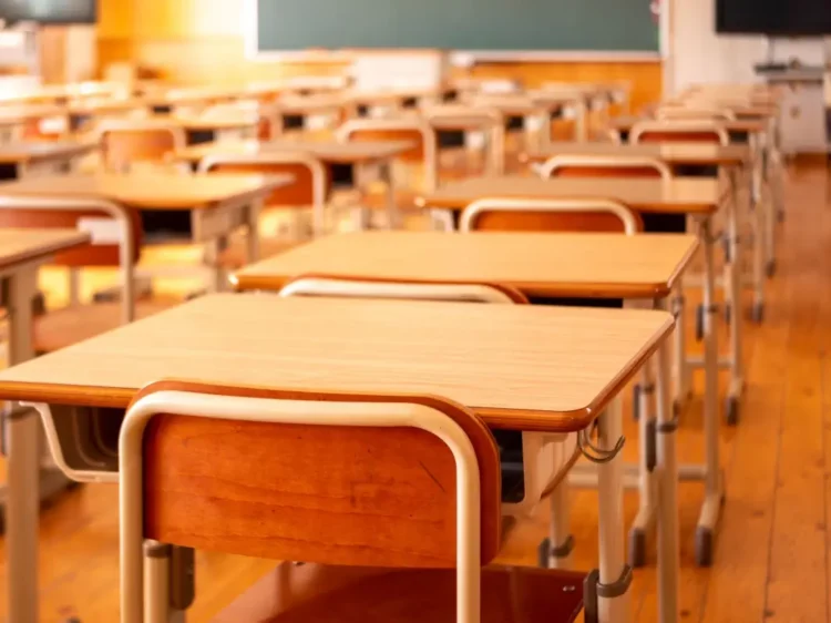 Aula scolastica vuota con banchi e sedie disposti davanti alla lavagna