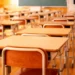 Aula scolastica vuota con banchi e sedie disposti davanti alla lavagna
