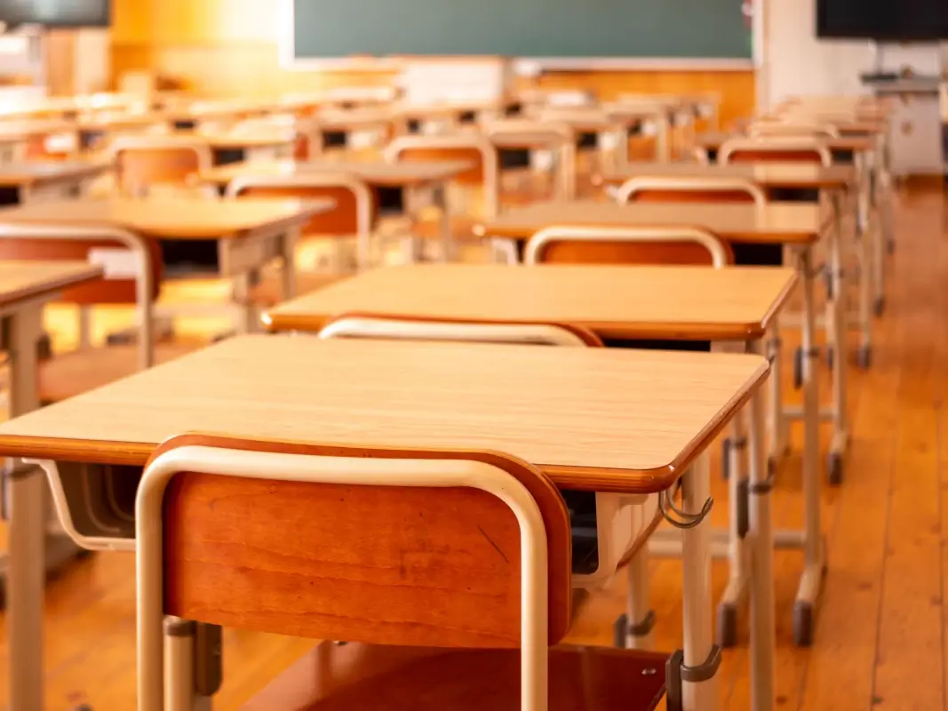 Aula scolastica vuota con banchi e sedie disposti davanti alla lavagna
