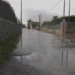 Strada allagata in via Pluchino a Modica: acqua piovana ristagna tra muretti a secco sotto un cielo grigio