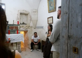 Visita a Scicli in una cappella: quattro persone vicino a un altare con candele rosse e a una targa San Guglielmo