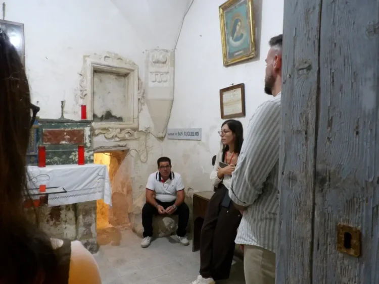 Visita a Scicli in una cappella: quattro persone vicino a un altare con candele rosse e a una targa San Guglielmo