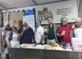 Gruppo di espositori assaggia prodotti da forno allo stand della mostra artigianale nel centro storico di Gangi.