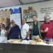 Gruppo di espositori assaggia prodotti da forno allo stand della mostra artigianale nel centro storico di Gangi.