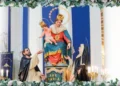 Simulacro della Madonna del Rosario con il Bambino tra due santi domenicani, su un altare ornato di fiori e candele
