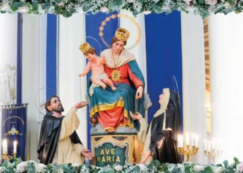 Simulacro della Madonna del Rosario con il Bambino tra due santi domenicani, su un altare ornato di fiori e candele