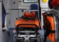 Interno di un'ambulanza con la barella arancione del 118 al centro e le attrezzature di soccorso sulla destra