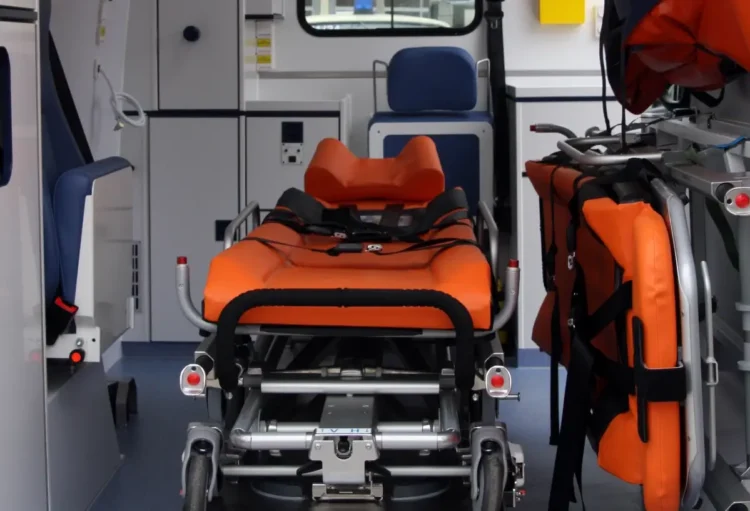 Interno di un'ambulanza con la barella arancione del 118 al centro e le attrezzature di soccorso sulla destra