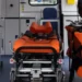 Interno di un'ambulanza con la barella arancione del 118 al centro e le attrezzature di soccorso sulla destra