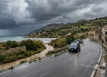 Cielo carico di nuvole temporalesche su una strada bagnata in Sicilia, allerta gialla. Immagine generata con intelligenza artificiale.