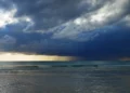 Nubi di maltempo e temporali si addensano sul mare, con pioggia visibile in lontananza