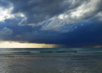 Nubi di maltempo e temporali si addensano sul mare, con pioggia visibile in lontananza