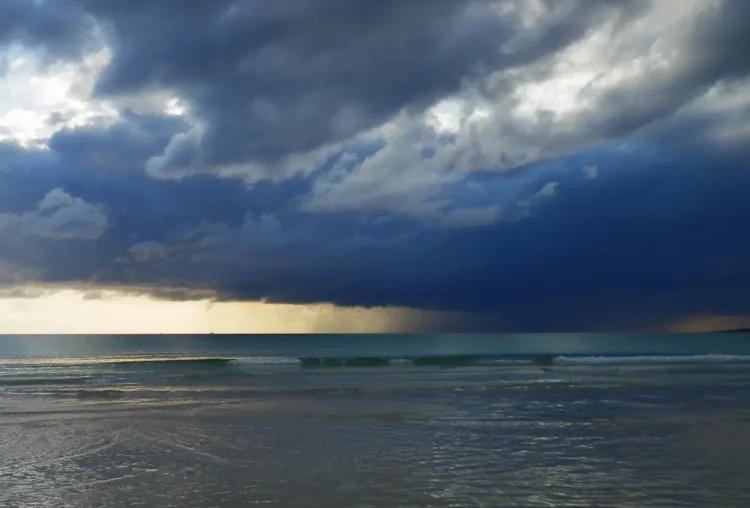 Nubi di maltempo e temporali si addensano sul mare, con pioggia visibile in lontananza