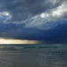 Nubi di maltempo e temporali si addensano sul mare, con pioggia visibile in lontananza