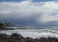 Mare in burrasca e cielo carico di nubi da temporali durante il maltempo su un lungomare con palme